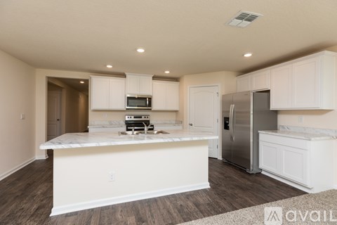 A kitchen with white cabinets and a marble island.