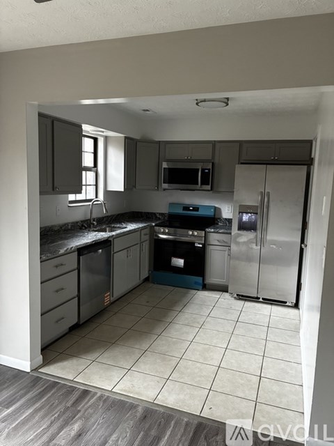 A kitchen with a refrigerator, sink, and stove.