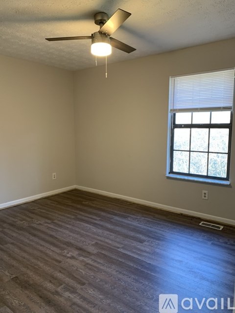 A room with a ceiling fan and a window with blinds.