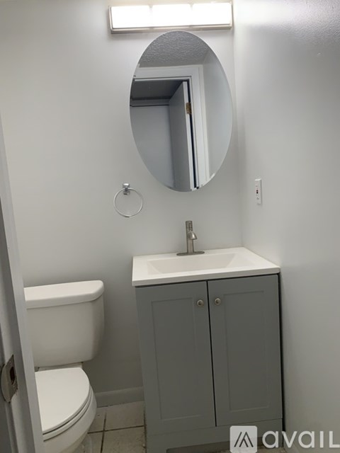 A bathroom with a toilet, sink and mirror.
