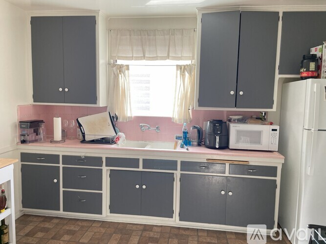 A kitchen with grey cabinets and a pink countertop.