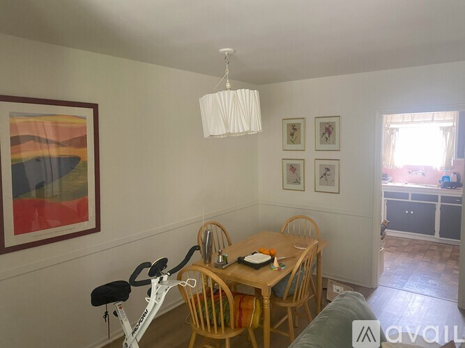 A dining room with a table, chairs, and a painting on the wall.