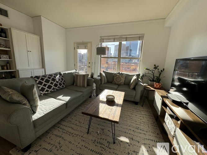 A living room with a grey couch, a coffee table, and a television.