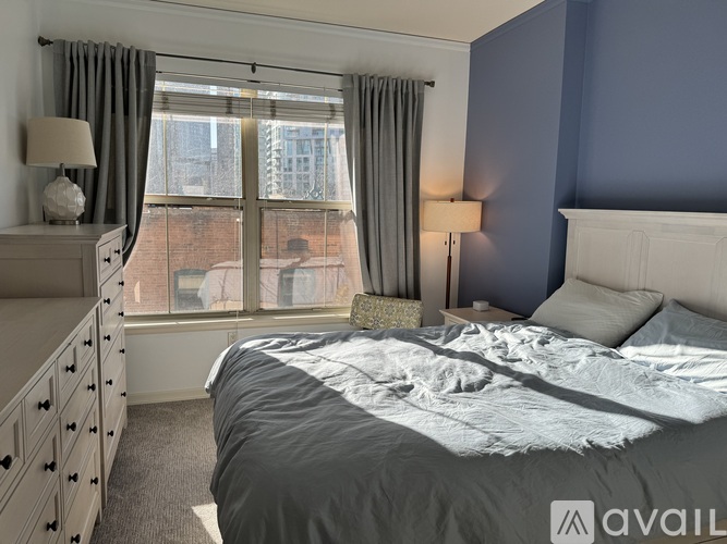 A bedroom with a large bed and a window with curtains.