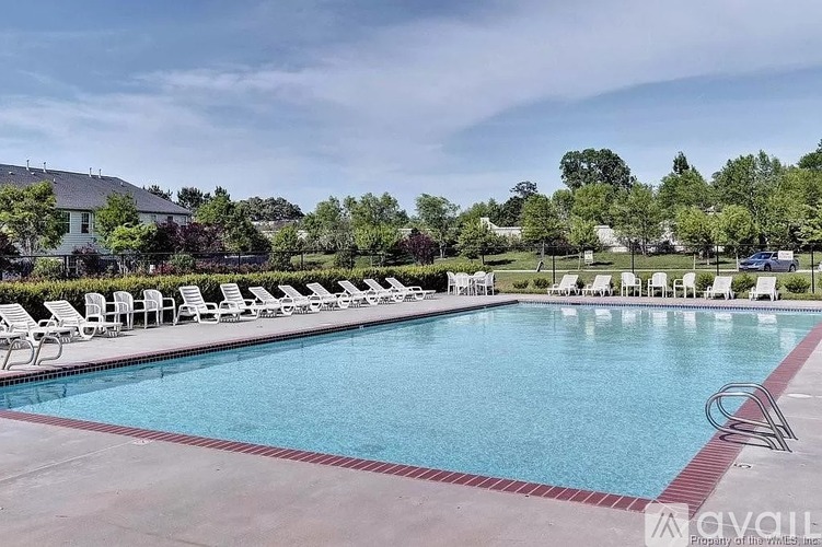A large swimming pool with lounge chairs around it.