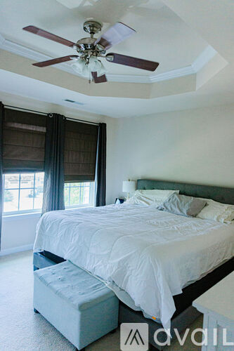 A bedroom with a bed, a ceiling fan, and a window with curtains.