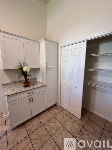A kitchen with white cabinets and a marble countertop.