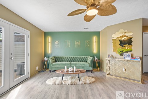A living room with a green sofa and a fan on the ceiling.