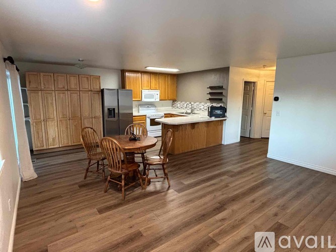 A kitchen with wooden floors and a dining table with chairs.