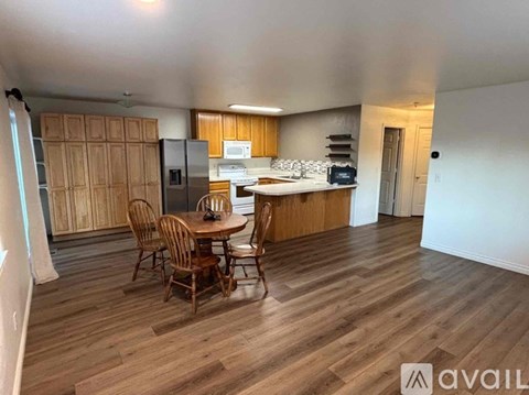 A kitchen with wooden floors and a dining table with chairs.