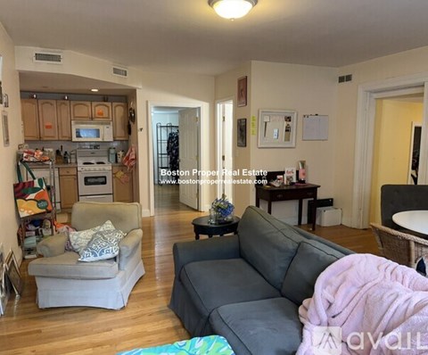 A living room with a grey couch and a kitchen area in the background.