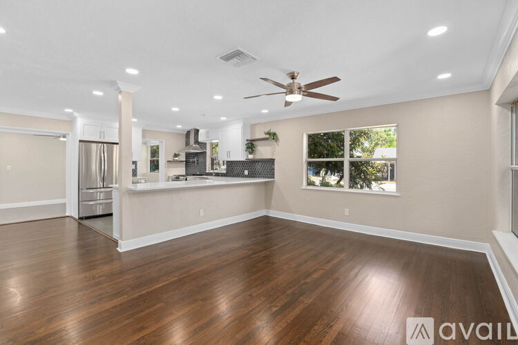 A spacious room with wooden floors and a ceiling fan.
