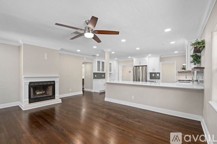 A spacious living room with a fireplace and a fan.