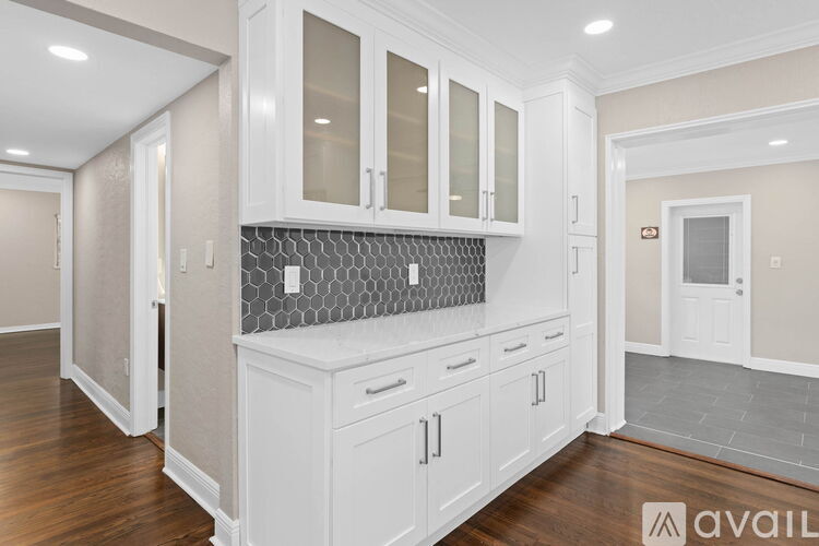 A kitchen with white cabinets and a grey backsplash.