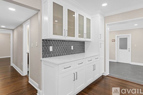 A kitchen with white cabinets and a grey backsplash.