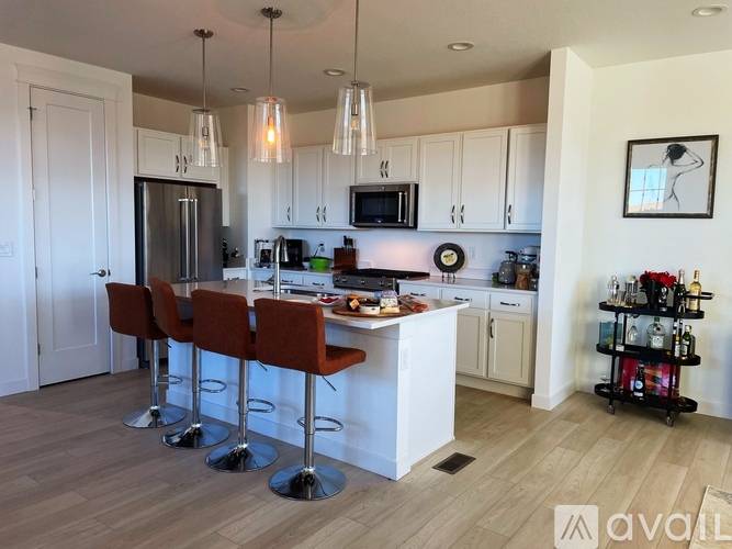 A kitchen with white cabinets and a bar area with red stools.