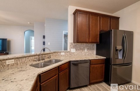 A kitchen with a black refrigerator and brown cabinets.