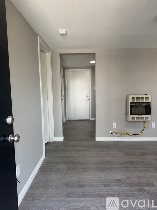 A hallway with a black door and a white door at the end.