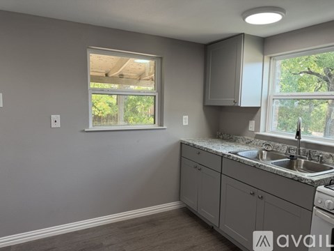 A kitchen with grey cabinets and a window.