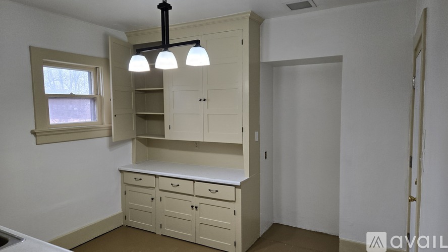 A kitchen with a window, cabinets, and a countertop.
