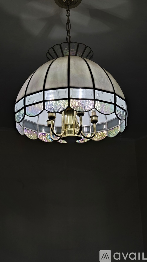 A chandelier with a black metal frame and glass panels is hanging from the ceiling.