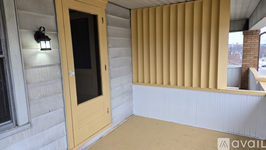 A house entrance with a wooden door and a window with yellow blinds.