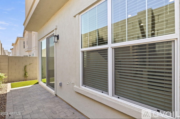 A modern house with a grey tiled walkway leading to a glass door.