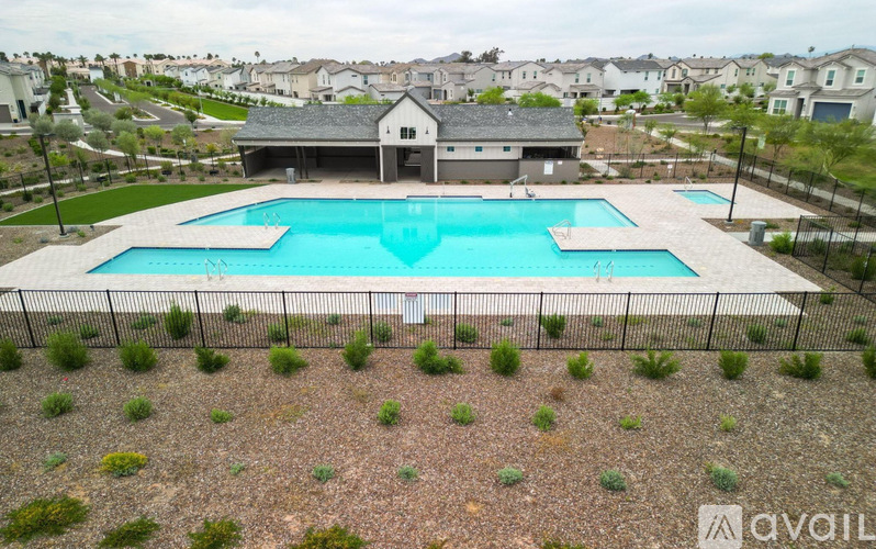 A large swimming pool surrounded by a fence and a house in the background.
