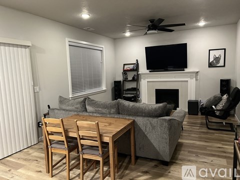 A living room with a grey couch, a wooden table, and a television mounted above the fireplace.