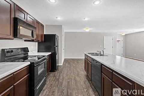 A kitchen with dark wood cabinets and black appliances.