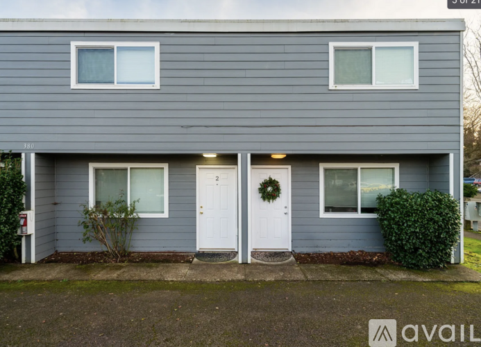 A grey house with a white door and a wreath on the door.