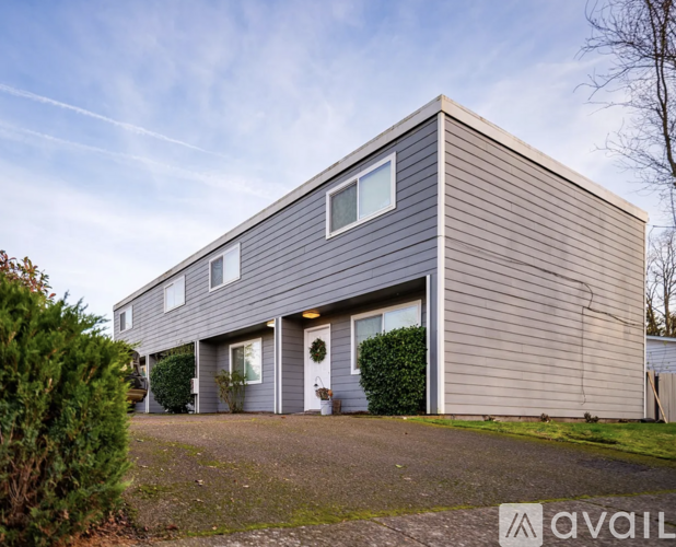 A modern house with a grey exterior and a large front yard.