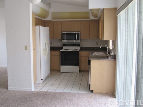 A kitchen with a white refrigerator, black oven, and a microwave above the stove.