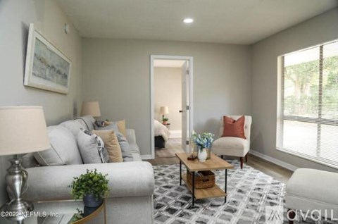 A living room with a grey couch, a coffee table, and a painting on the wall.