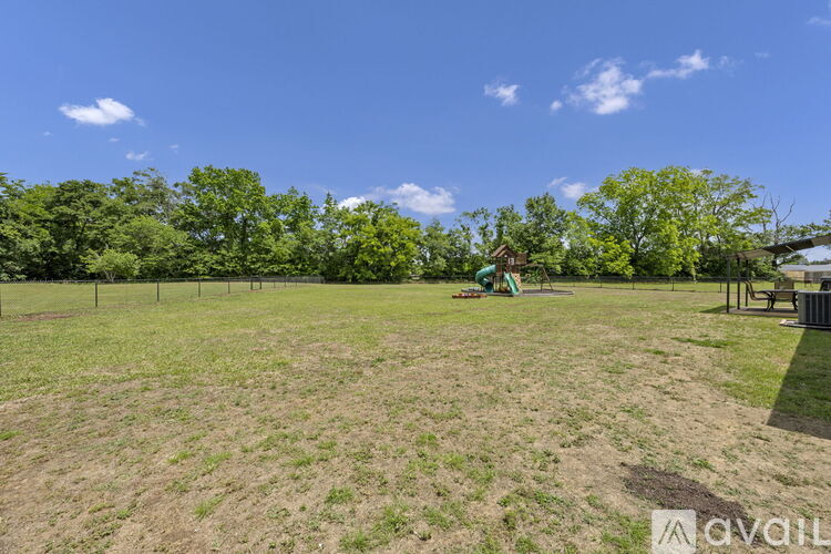 A field with a fence and trees in the background.