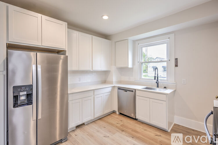A kitchen with a stainless steel refrigerator and white cabinets.