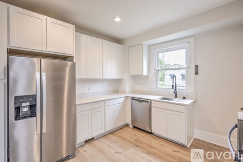 A kitchen with a stainless steel refrigerator and white cabinets.
