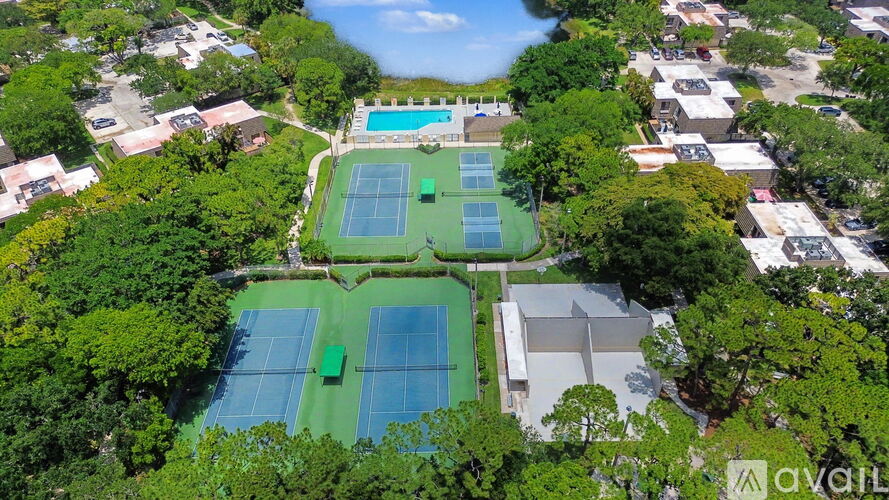 An aerial view of a tennis court surrounded by trees and buildings.