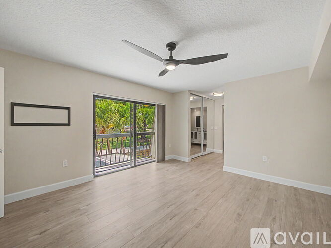 A spacious room with a ceiling fan and sliding glass doors leading to a patio.
