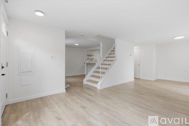 A spacious room with a staircase and wooden flooring.