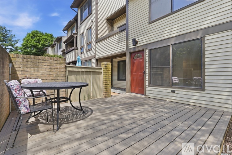 A wooden deck with a table and chairs is in front of a building.