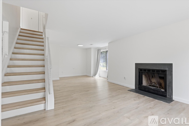 A spacious living room with a fireplace and a staircase.