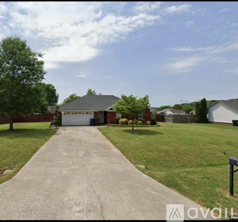A driveway leads to a garage with a house and trees in the background.