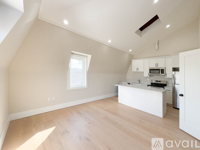 A spacious attic room with a kitchenette and a window.