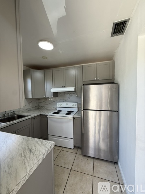 A kitchen with a stove, refrigerator, and cabinets.