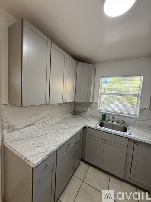 A kitchen with grey cabinets and a marble countertop.