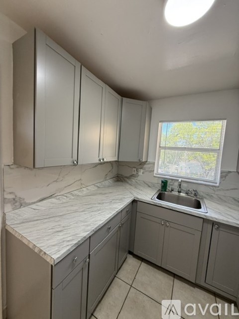 A kitchen with grey cabinets and a marble countertop.