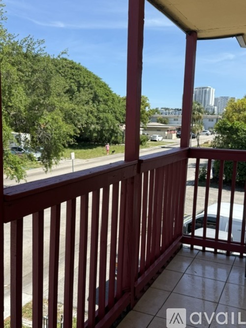 A balcony with a view of a parking lot and trees.