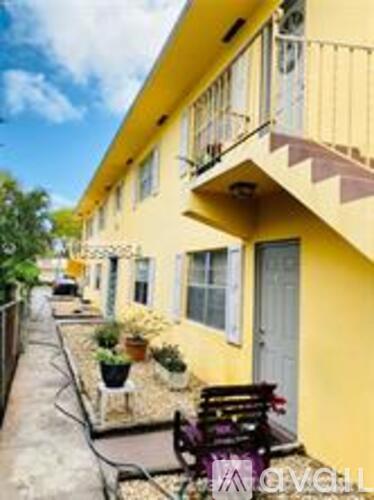 A yellow building with a balcony and a small garden in front.