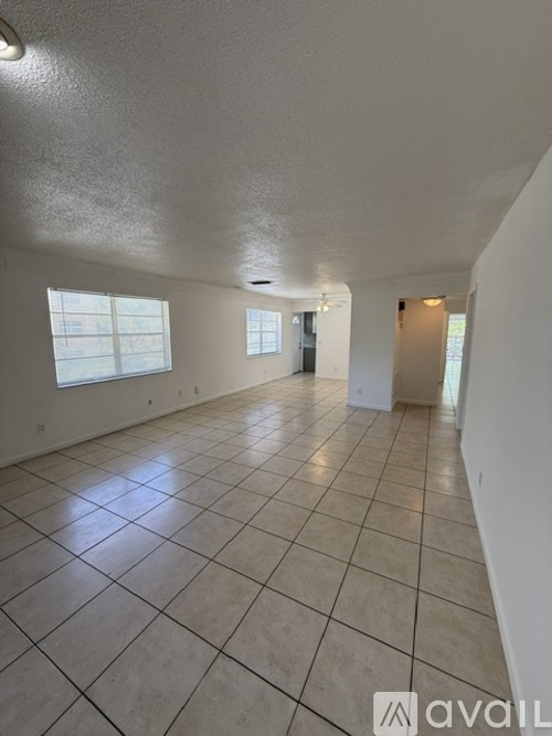 A spacious room with tiled flooring and large windows.